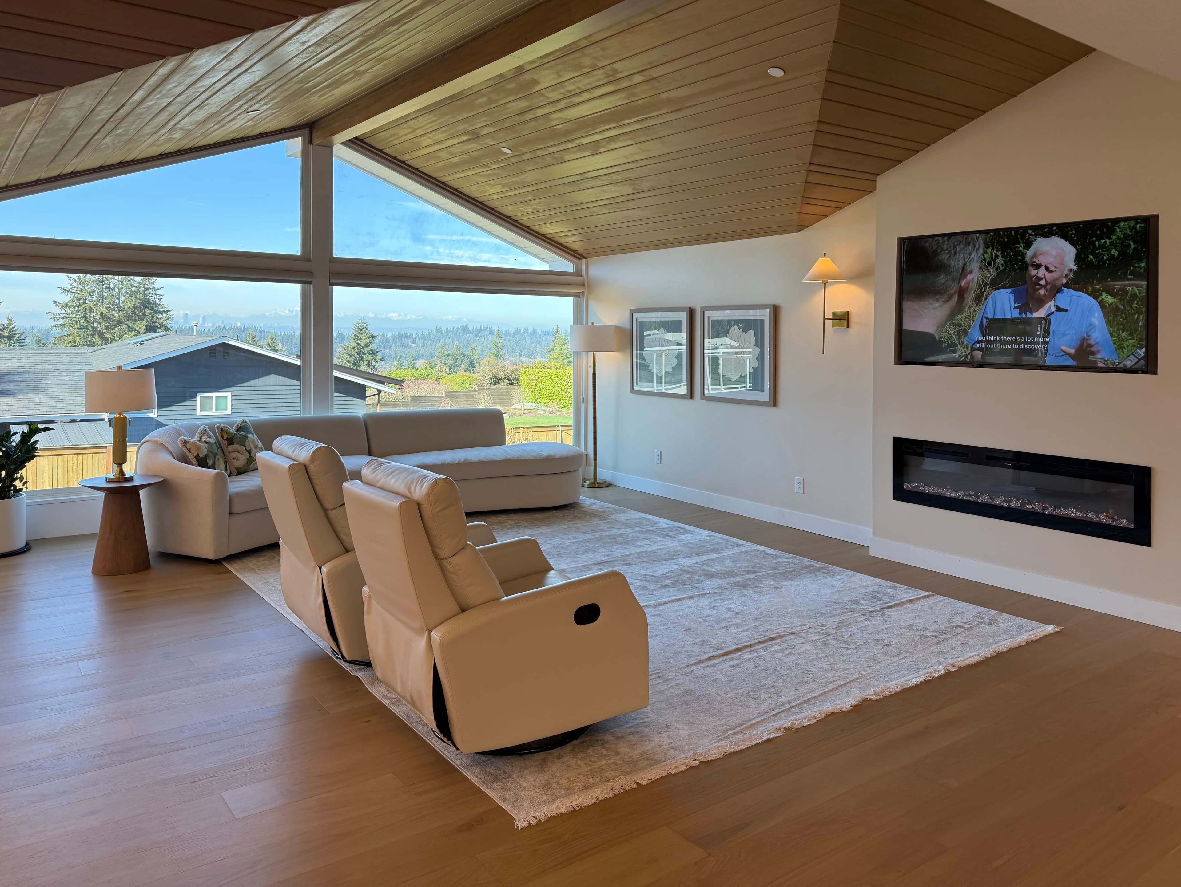 Living room at Norwood House with a fireplace, neutral upholstered seating, and natural light.